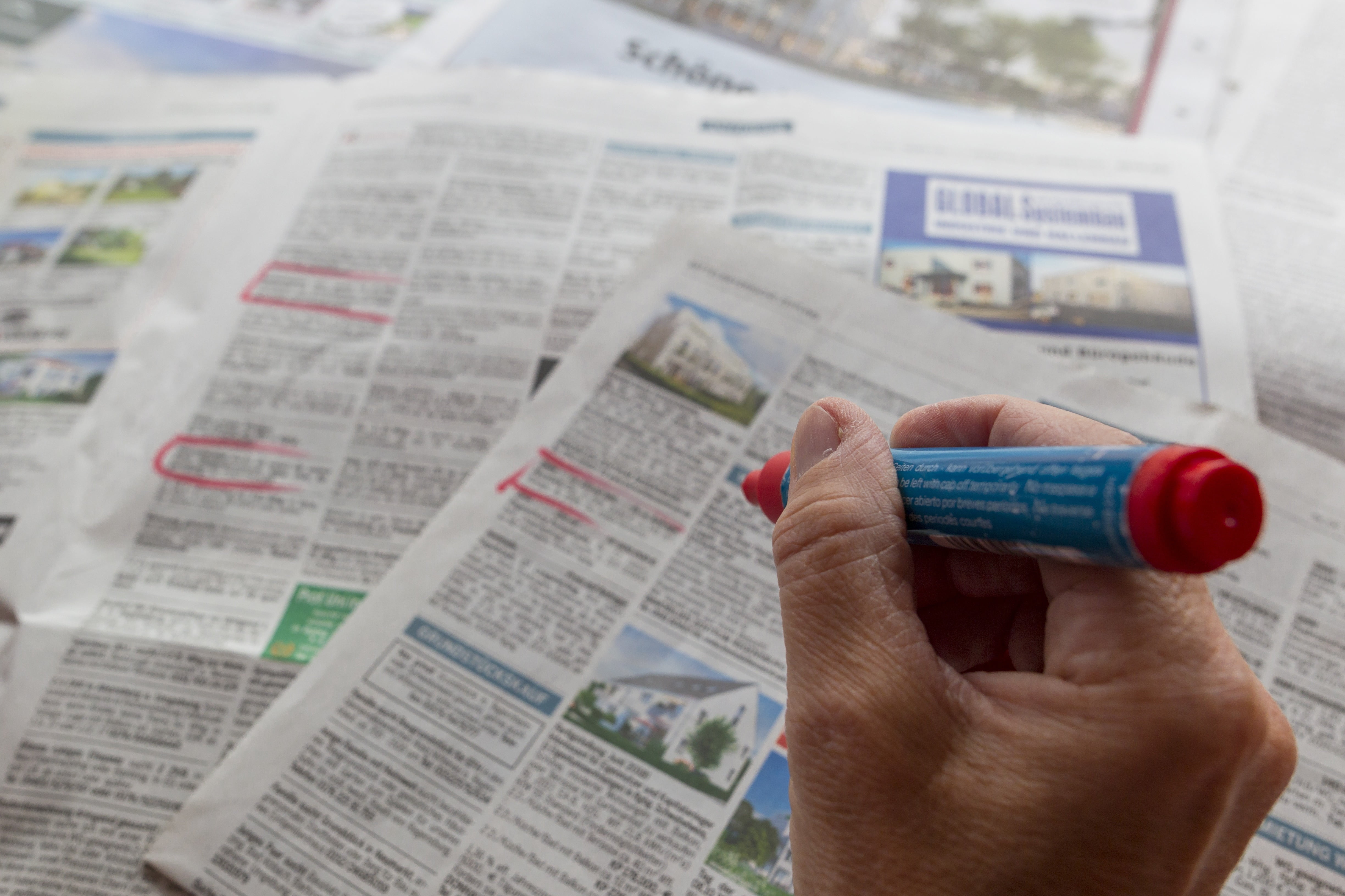 newspaper search for properties,  marker in hand with listings circled